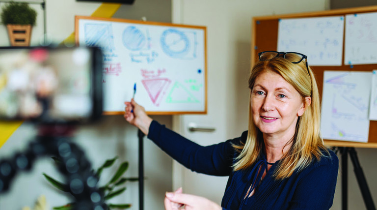 woman pointing at whiteboards and camera